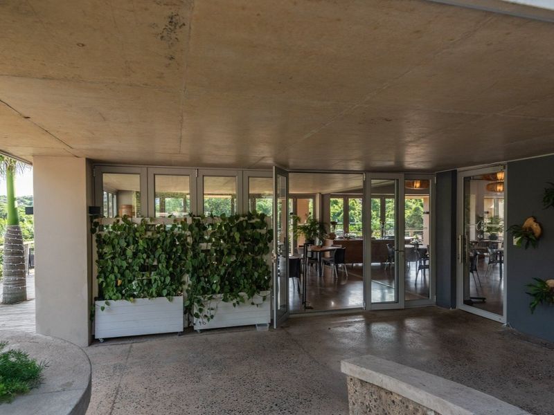 A spacious covered patio featuring exposed aggregate flooring, a concrete ceiling, and large glass doors providing seamless access to the interior living area.