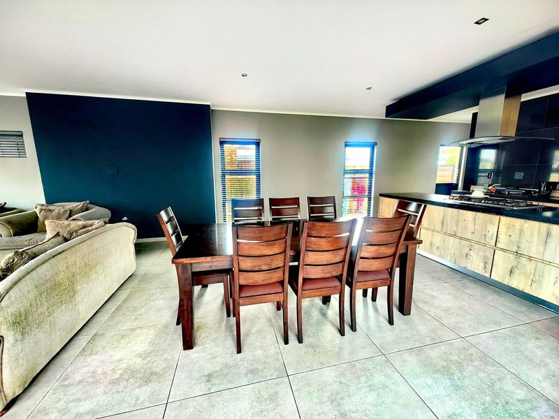 Modern open-plan living and dining area featuring large format floor tiles, recessed lighting, and a contemporary kitchen with built-in cabinetry and gas hob.