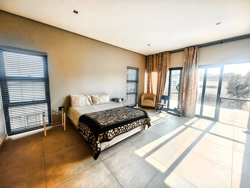 Spacious bedroom featuring large format floor tiles, recessed lighting, and expansive aluminium sliding doors providing direct access to the outdoor area.
