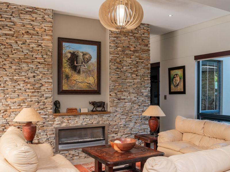Spacious living room featuring a prominent stone-clad feature wall with a built-in fireplace, recessed lighting, and large windows providing natural light.
