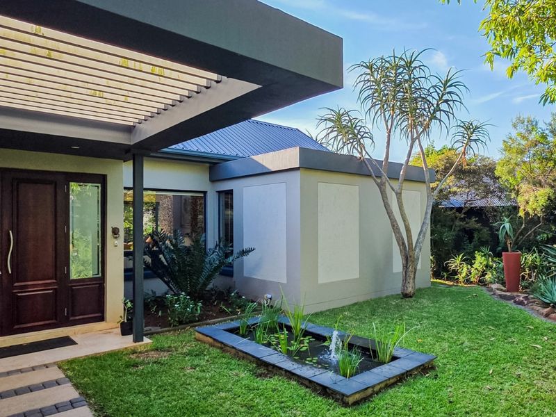 Modern front entrance featuring a covered pergola, double timber doors, and a landscaped garden with a built-in water feature.