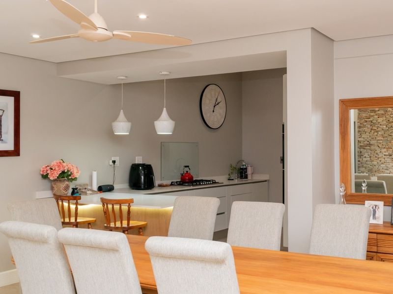 Open-plan dining area featuring a modern kitchen with stone countertops, gas hob, and elegant pendant lighting, seamlessly integrated into the living space.
