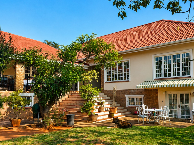 Rear view of a traditional house featuring a terracotta tiled roof, brick and rendered facade, multi-pane windows, and a paved patio area.