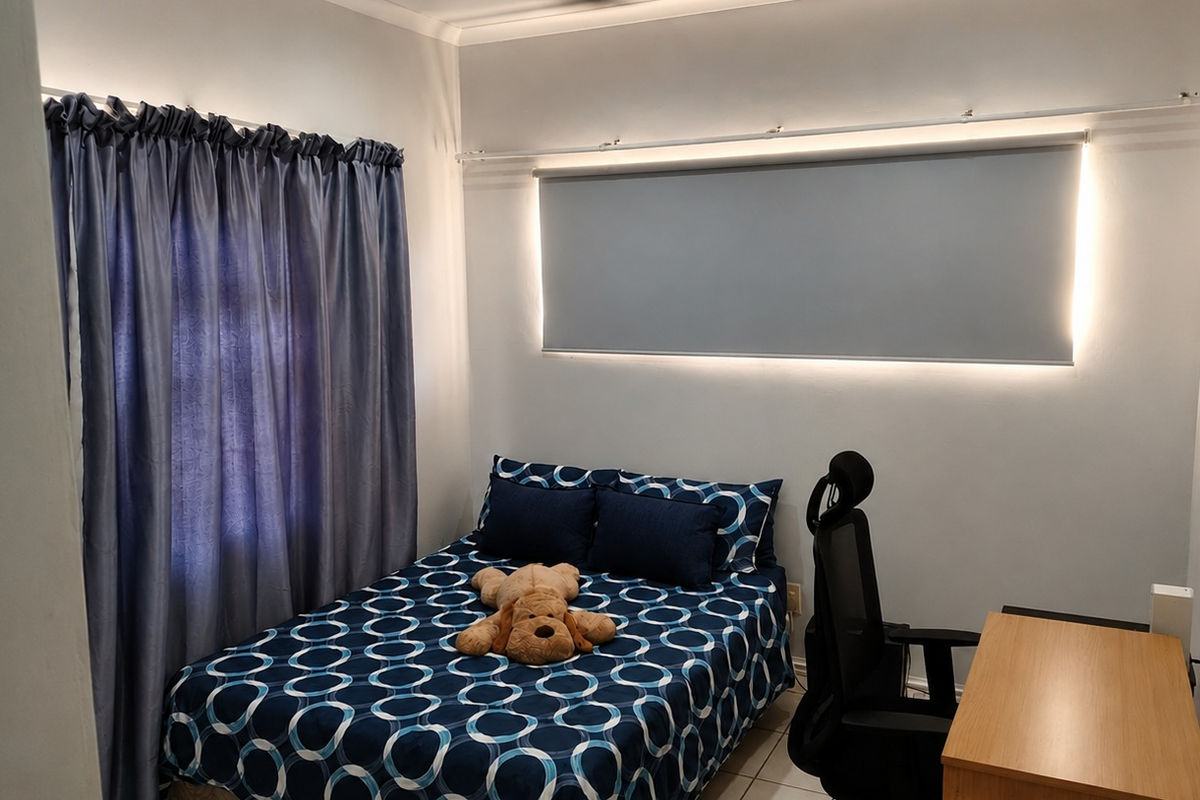 A well-maintained bedroom featuring tiled flooring, a modern roller blind with integrated wall lighting, and a curtain track for window treatments.