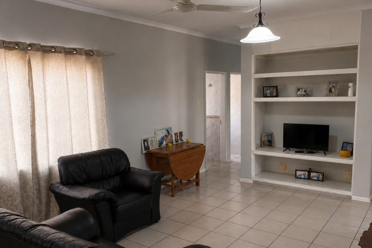 A living room featuring tiled flooring, a built-in shelving unit, and a ceiling fan, offering a functional space with neutral wall tones.