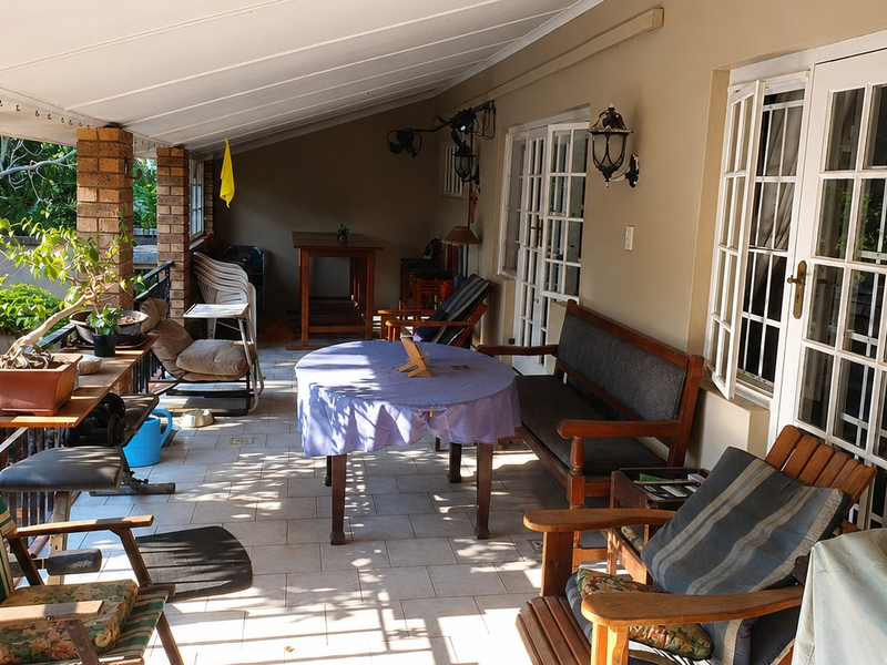 A covered patio area featuring brick pillars, tiled flooring, and multiple sets of french doors providing access to the interior.