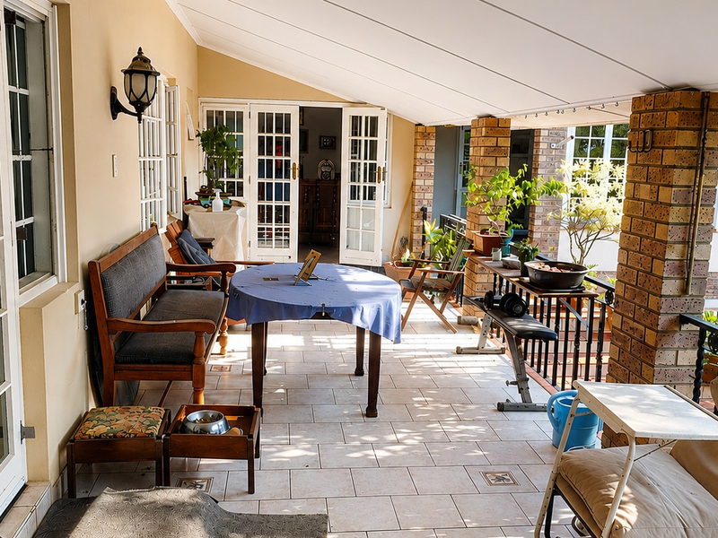 A spacious covered patio featuring tiled flooring, brick support pillars, and multiple sets of french doors providing access to the interior living spaces.