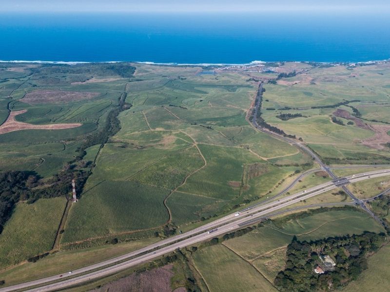 An expansive aerial view of the farm property, showcasing vast agricultural fields, a major highway intersection, and proximity to the coastline.