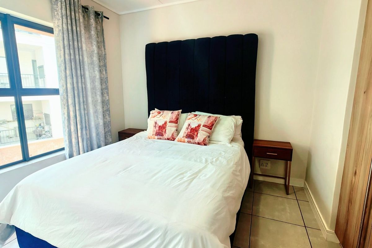 A well-lit bedroom featuring tiled flooring, a ceiling fan, and a built-in cupboard, offering a comfortable and functional living space.