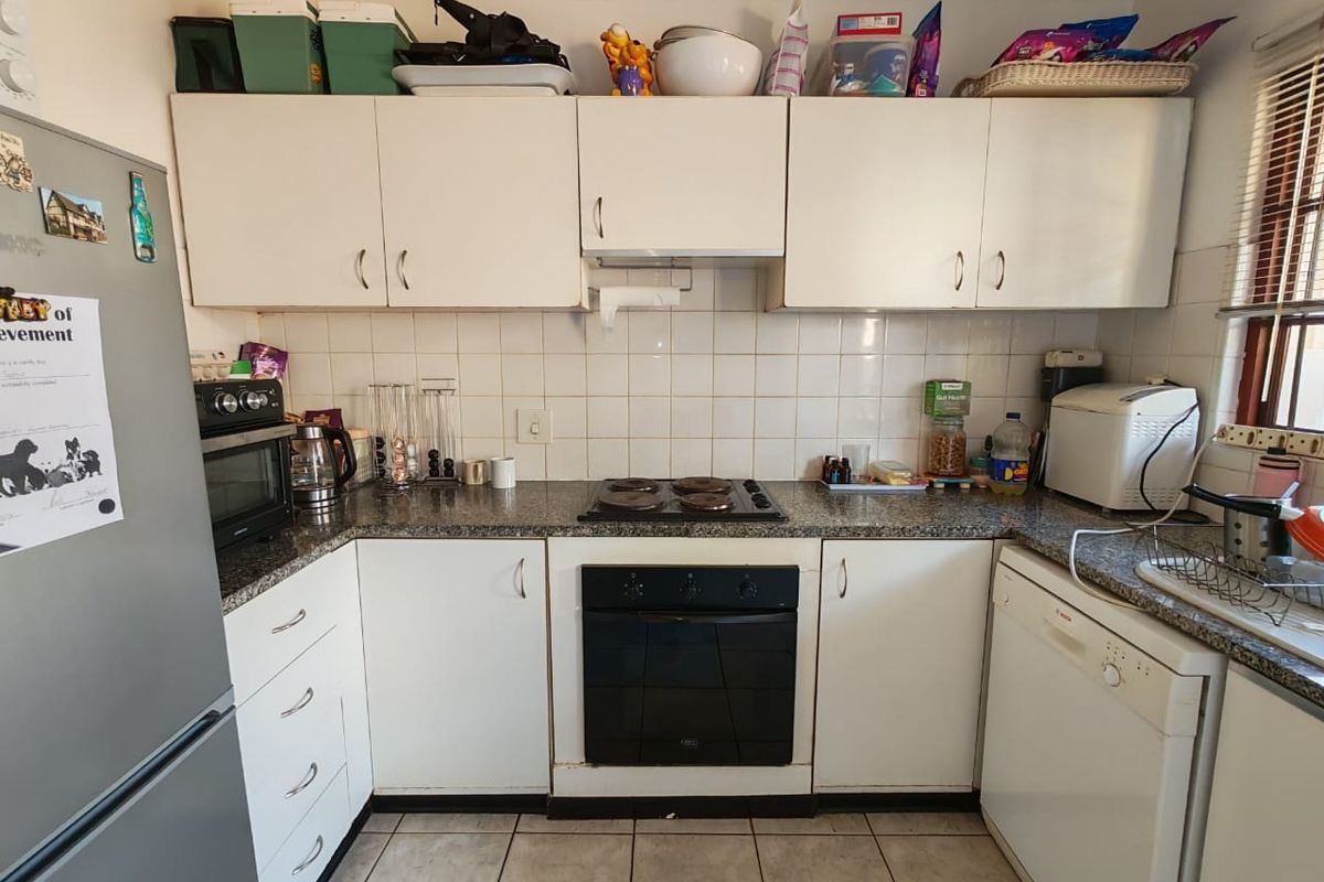 A functional kitchen featuring white cabinetry, granite countertops, a ceramic tile backsplash, and built-in oven and hob appliances.