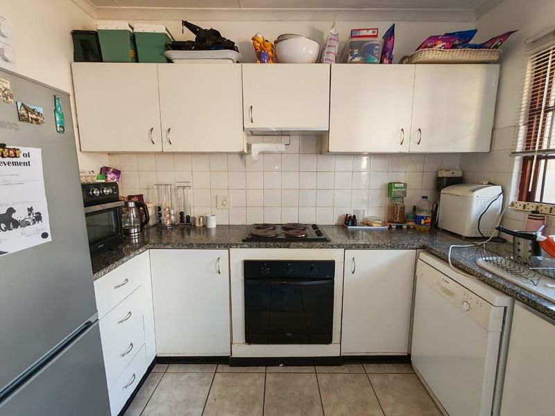 A functional kitchen featuring white cabinetry, granite countertops, a ceramic tile backsplash, and built-in oven and hob appliances.