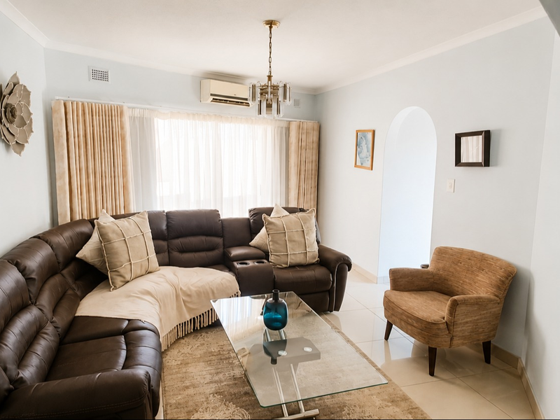 A well-maintained living room featuring tiled flooring, a split-system air conditioner, and a classic architectural archway leading to adjacent spaces.