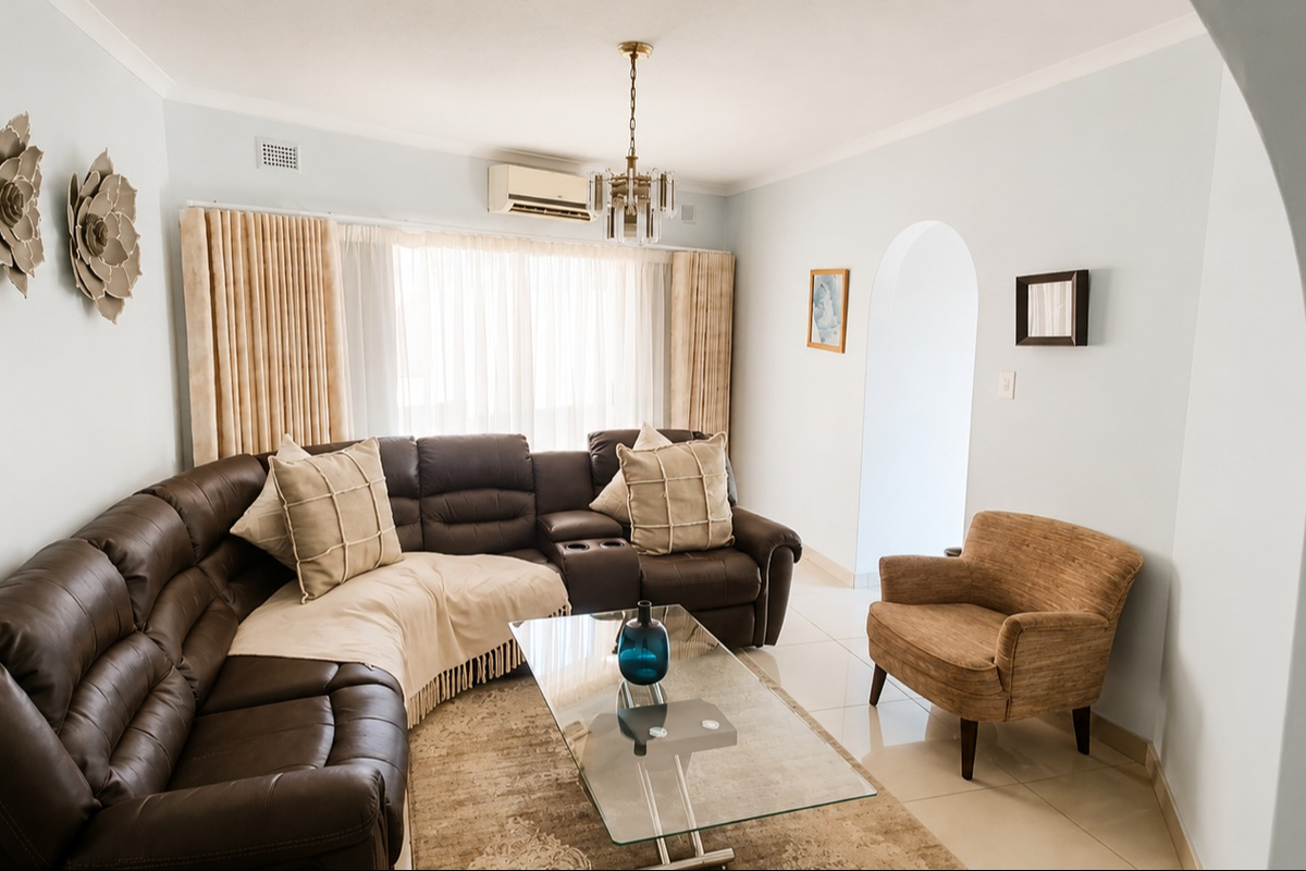 A well-maintained living room featuring tiled flooring, a split-system air conditioner, and a classic architectural archway leading to adjacent spaces.