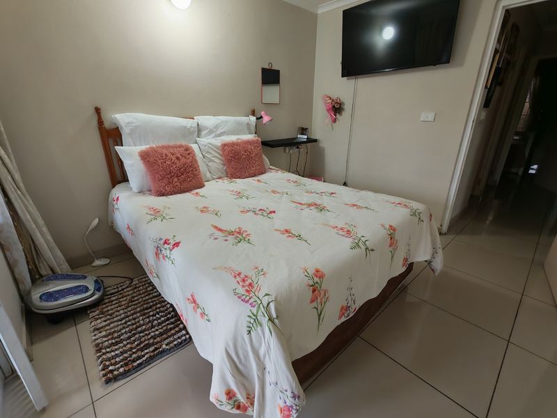 A functional bedroom featuring tiled flooring and a wall-mounted television, offering a neutral base for personalization.