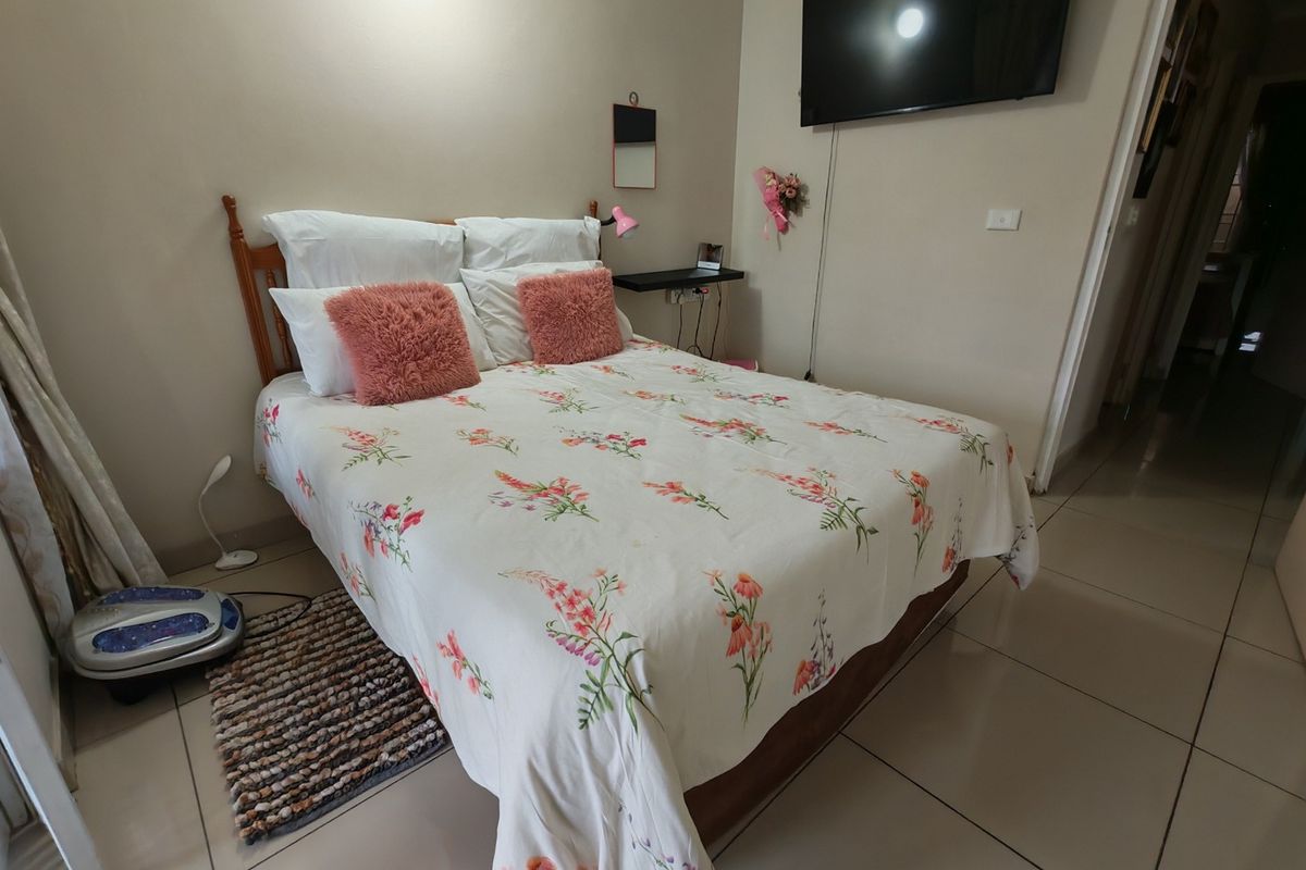 A functional bedroom featuring tiled flooring and a wall-mounted television, offering a neutral base for personalization.