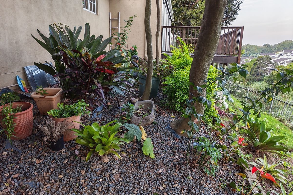 A rear garden area featuring gravel landscaping, established plants, and a raised wooden deck overlooking the surrounding neighborhood.