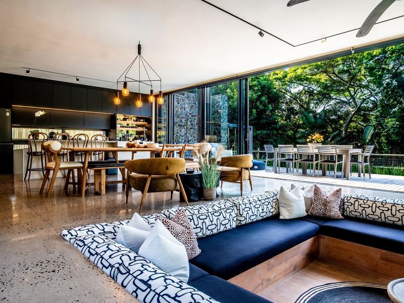 Spacious open-plan living and kitchen area featuring polished concrete floors, modern built-in cabinetry, and seamless indoor-outdoor flow through large sliding glass doors.