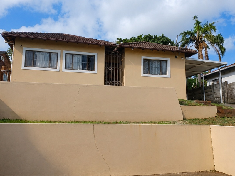 Front elevation of a single-story house featuring a tiled roof, security gate, and tiered retaining walls.