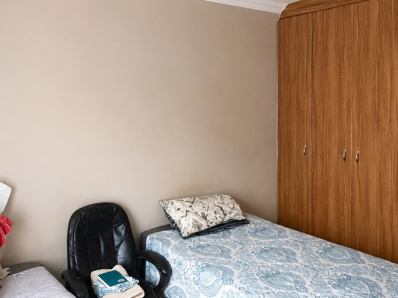 A bedroom featuring neutral wall finishes and functional wood-grain built-in cupboards providing ample storage space.