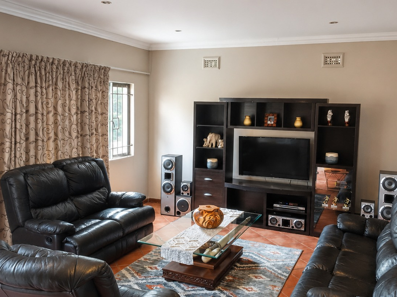 A comfortable living room featuring terracotta floor tiles, coved ceilings with recessed lighting, and secure window fittings.
