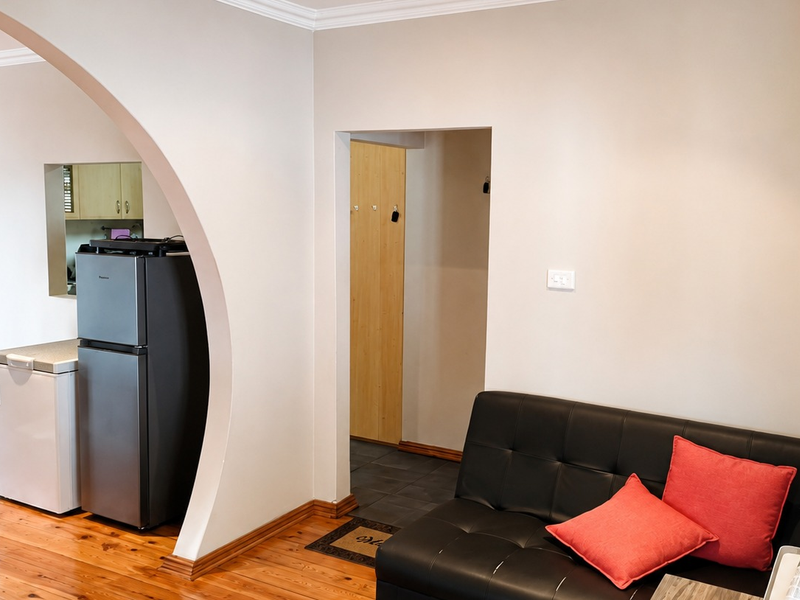 Open plan living area featuring polished timber flooring, a distinctive architectural archway, and neutral wall finishes.