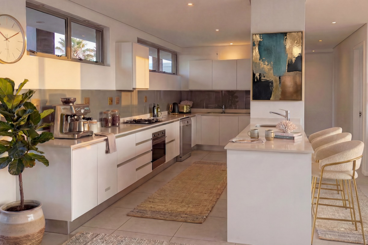 Modern kitchen featuring sleek white cabinetry, stone countertops, a central island with seating, and high-quality built-in appliances in a bright, open-plan layout.