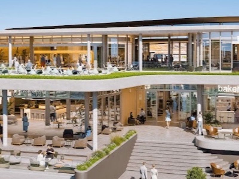 A modern multi-level commercial or clubhouse facility featuring expansive glass facades, covered outdoor seating areas, and a landscaped roof terrace.