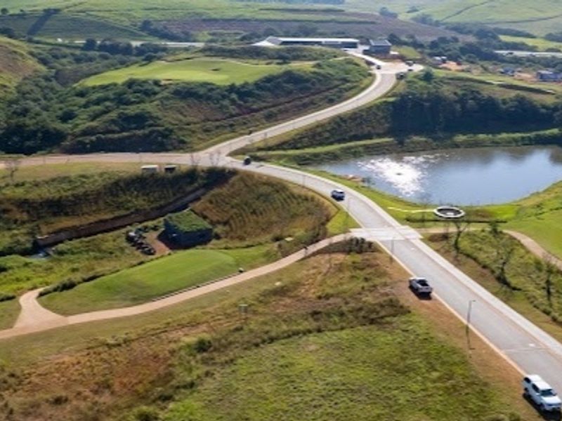 An aerial view of the residential vacant land property, showcasing the surrounding landscape, access roads, and nearby water feature.