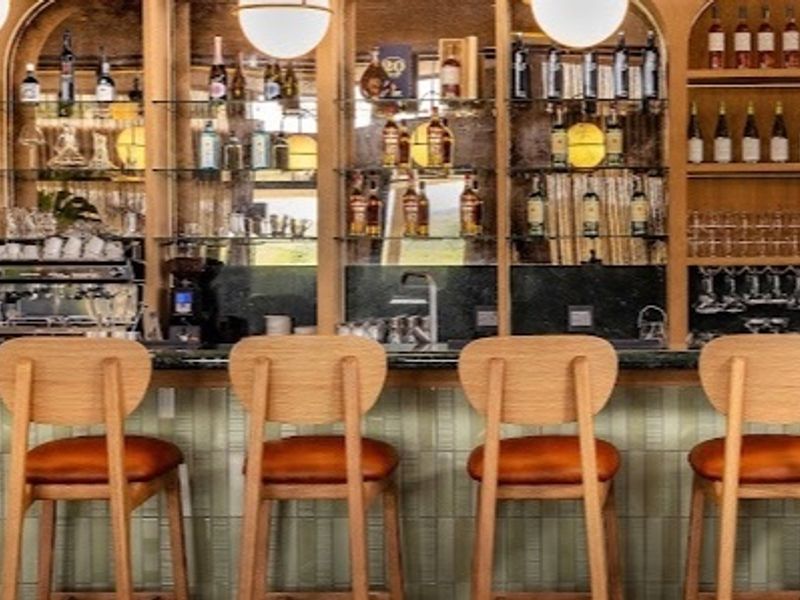 A sophisticated, well-appointed bar area featuring custom built-in shelving, integrated lighting, and a high-quality stone counter with decorative tiled detailing.