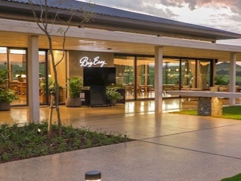 A spacious covered patio featuring polished concrete flooring, stone structural elements, and large sliding glass doors opening into the main building area.