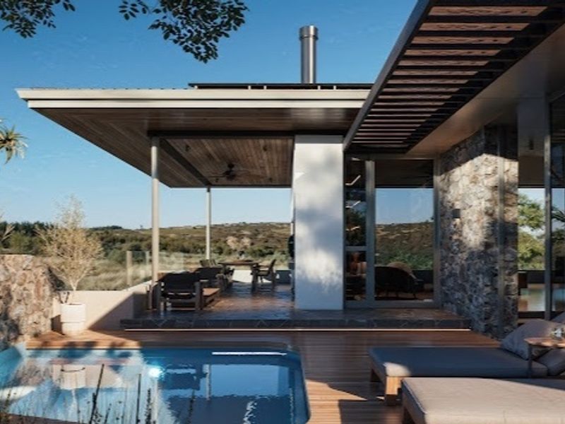 Modern outdoor living area featuring a swimming pool, timber decking, stone-clad walls, and a spacious covered patio with scenic landscape views.