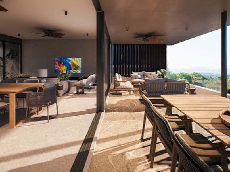 A spacious covered patio featuring stone flooring, recessed lighting, and ceiling fans, seamlessly connecting to the interior living area with expansive views.