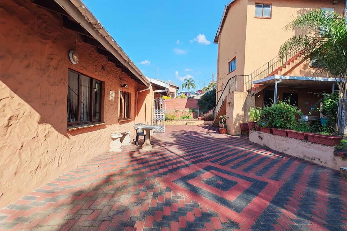 Spacious rear courtyard featuring patterned brick paving, an external staircase, and multi-level exterior walls with textured plaster finish.