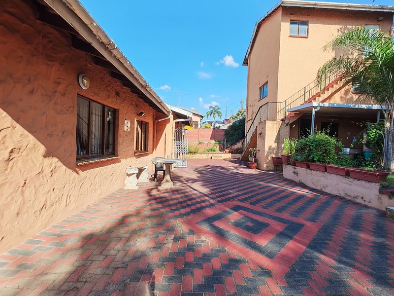 Spacious rear courtyard featuring patterned brick paving, an external staircase, and multi-level exterior walls with textured plaster finish.