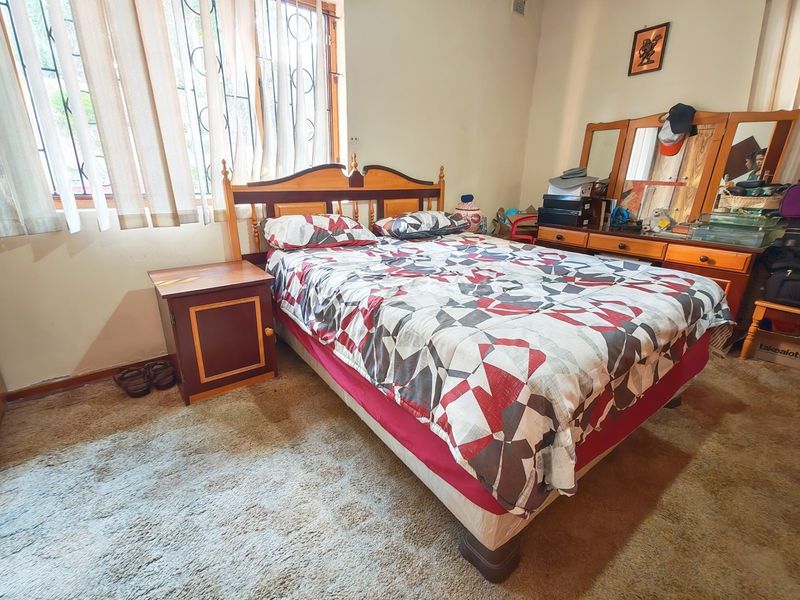 A bedroom featuring carpet flooring and a window fitted with security bars, offering a functional space ready for modernization.