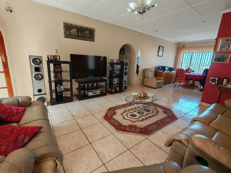 Spacious open-plan living and dining area featuring tiled flooring, an arched transition, and natural light through a large sliding glass door.