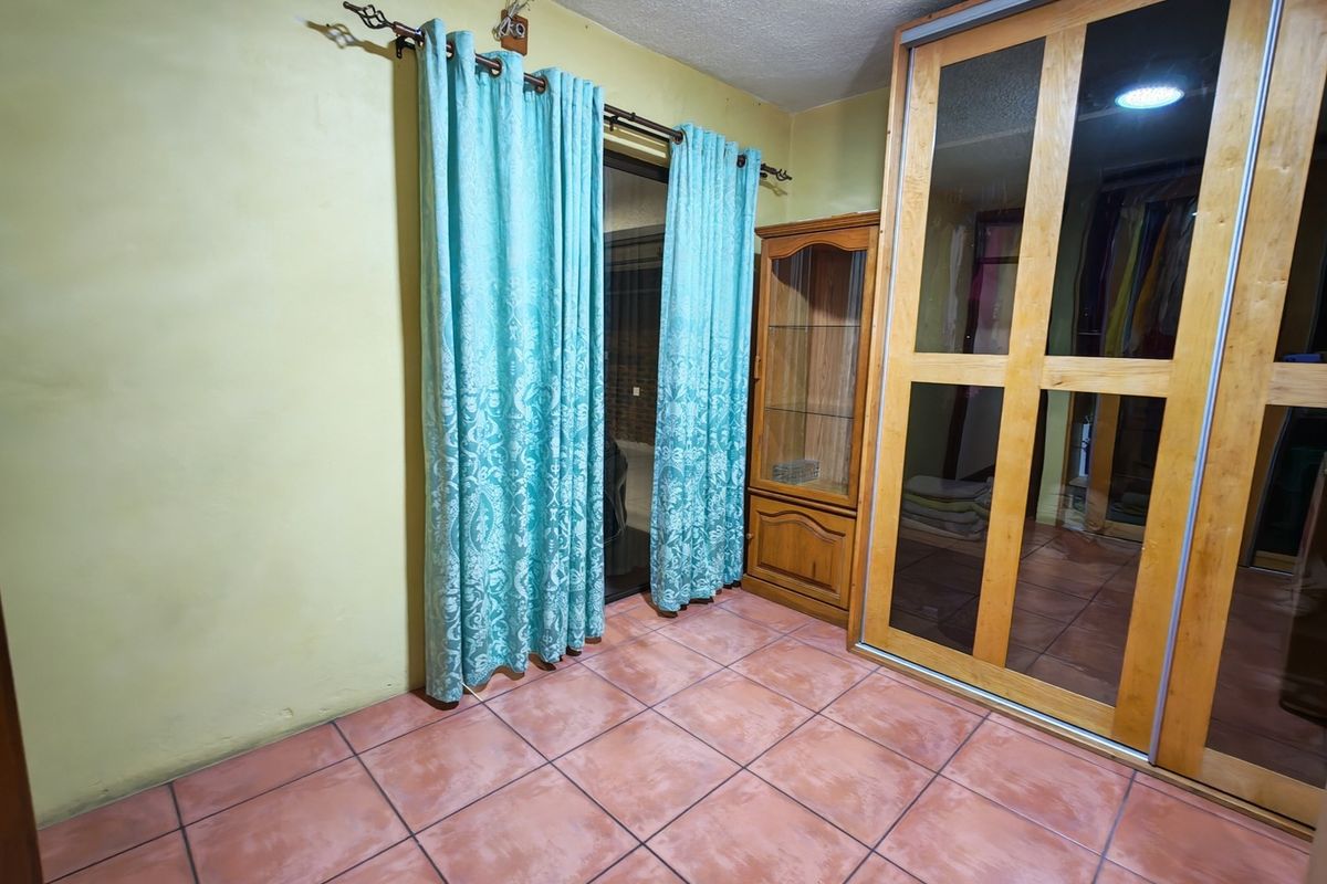 Bedroom featuring tiled flooring, a large built-in wardrobe with sliding doors, and direct access to an outdoor area via a sliding glass door.