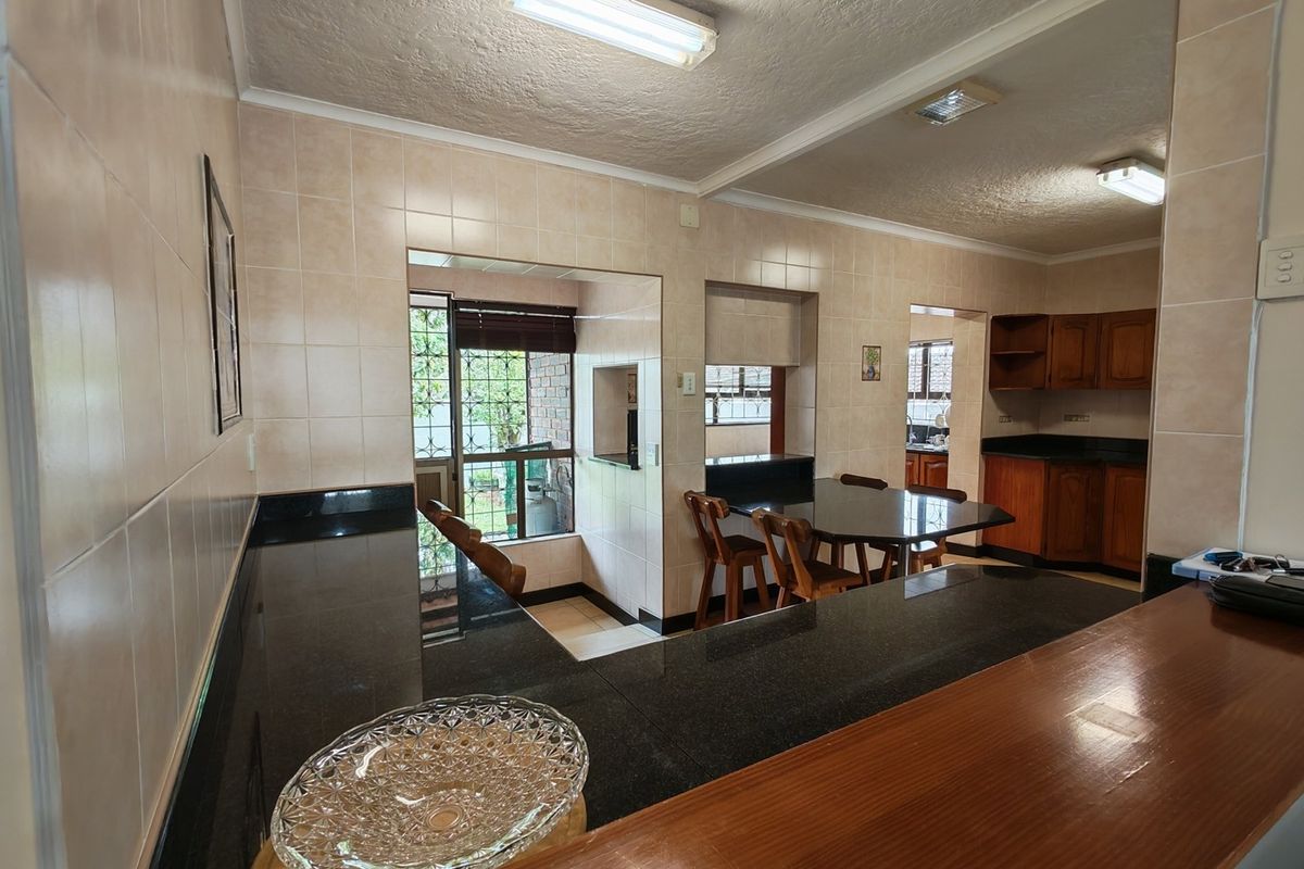 A functional kitchen featuring granite countertops, tiled walls, and built-in wooden cabinetry with an integrated breakfast bar area.