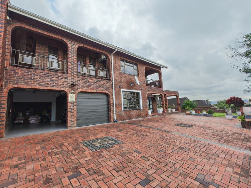 A well-maintained double-story face brick house featuring a spacious paved driveway, integrated double garage, and upper-level balcony access.