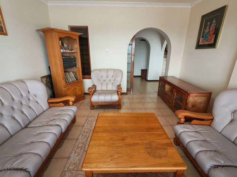 A living room featuring tiled flooring, a decorative archway leading to an adjacent space, and coved ceiling detailing.