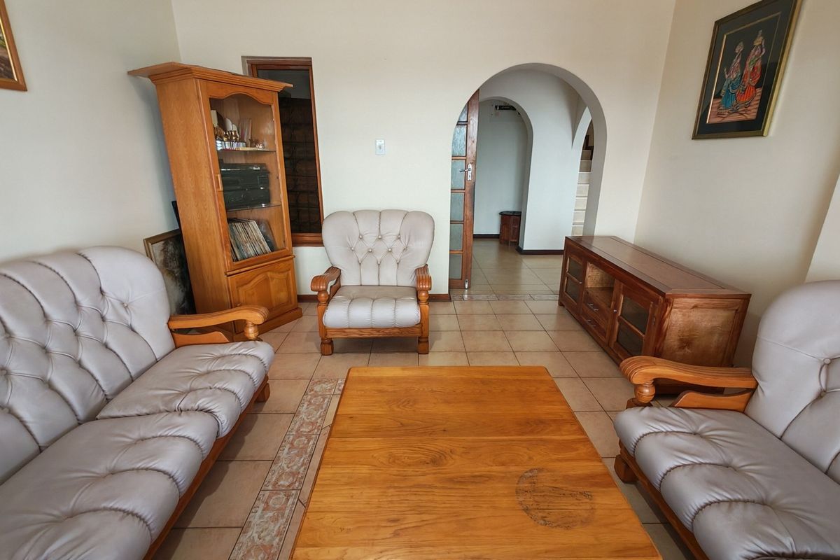 A living room featuring tiled flooring, a decorative archway leading to an adjacent space, and coved ceiling detailing.