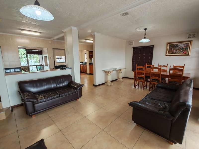 Spacious open-plan living and dining area featuring tiled flooring, neutral walls, and a convenient pass-through window connecting to the kitchen.