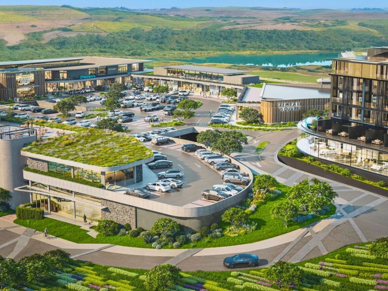 An aerial view of a modern commercial development featuring retail spaces, extensive parking facilities, and landscaped green roofs within a scenic estate setting.