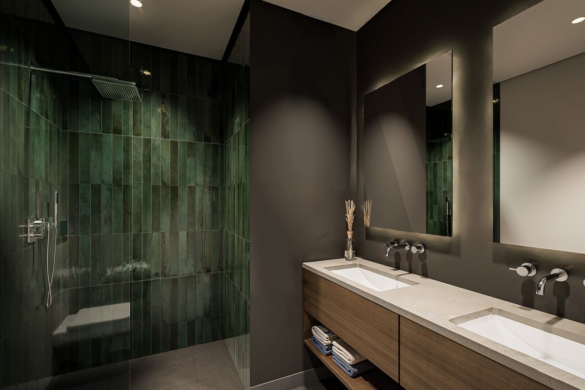 Modern luxury bathroom featuring a double vanity with stone countertop, wall-mounted faucets, backlit mirrors, and a spacious walk-in shower with green feature tiling.