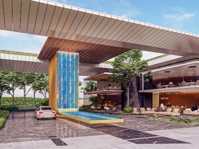 A modern architectural entrance featuring a prominent water feature, expansive paved driveway, and a contemporary multi-level structure with integrated canopy design.