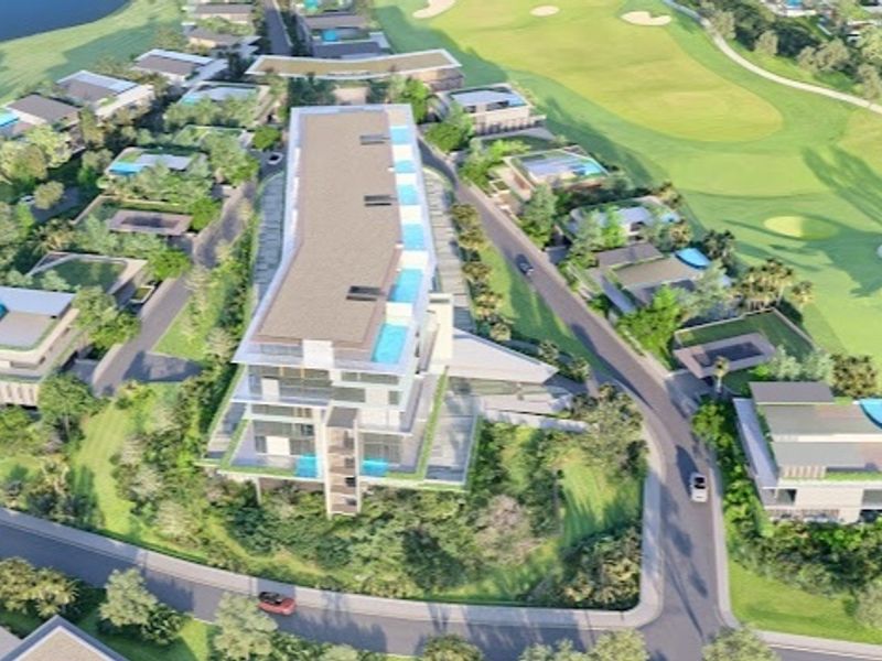 Aerial view of a modern residential development situated adjacent to a golf course, featuring multi-story buildings with private pools and landscaped surroundings.