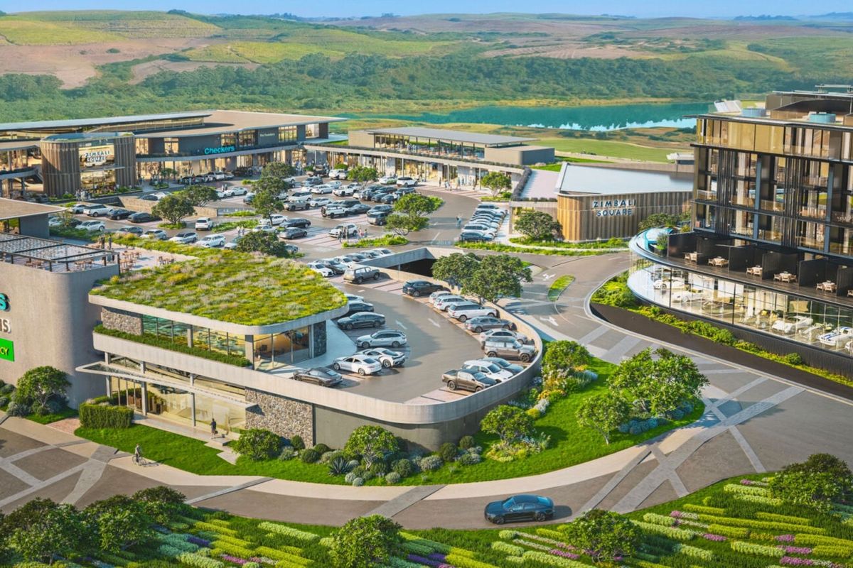 An aerial view of a modern commercial development featuring retail spaces, extensive parking facilities, and landscaped green roofs within a scenic estate setting.