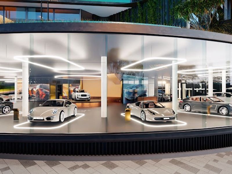 A modern, high-end luxury garage featuring a curved glass facade, structural columns, and integrated LED lighting displays.