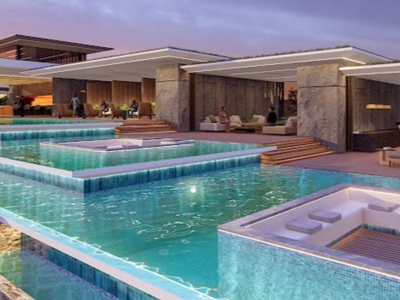 A luxurious multi-level swimming pool area featuring integrated sunken seating, stone architectural elements, and expansive timber decking for outdoor entertainment.