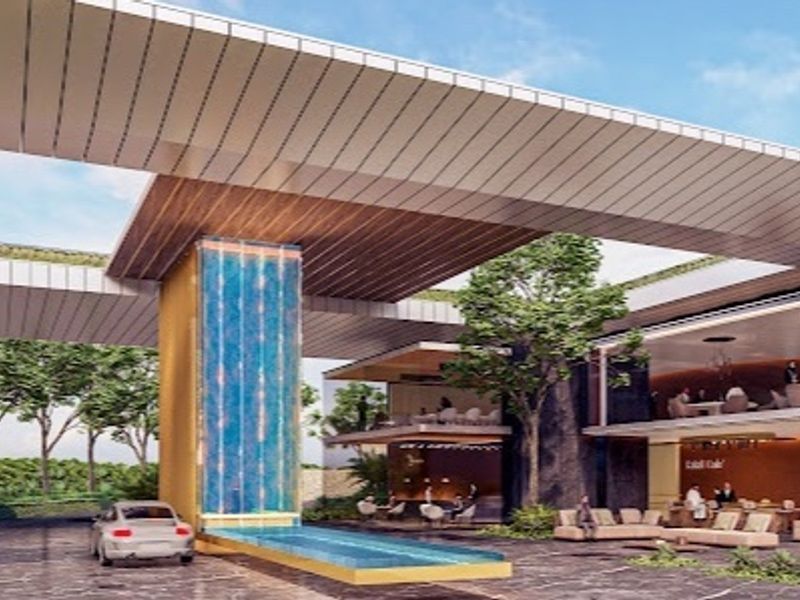 A modern architectural clubhouse entrance featuring a striking water feature, expansive covered driveway, and contemporary design elements.